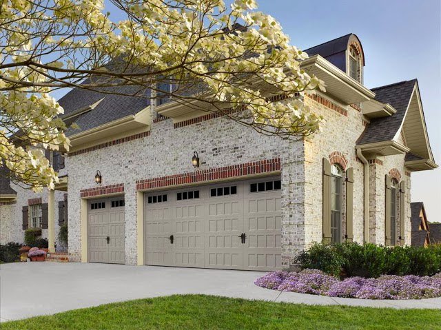 A large brick house featuring two light-colored garage doors installed by Precision Garage Door of Charleston in Charleston, SC.