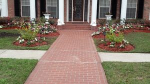 A brick pathway bordered by vibrant flower beds and a green lawn, maintained by Fresh Cuts Nola Lawn Service in New Orleans, LA.