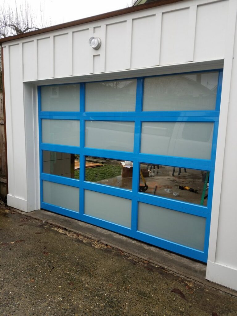 A bright blue modern garage door with frosted glass panels installed by Overhead Door Company of Everett, Inc in Everett, WA.
