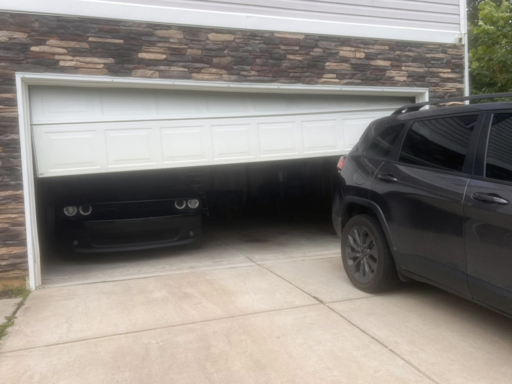 A broken and crooked garage door requiring repair services from 2BroGarage LLC in Charlotte, NC.