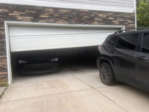 A broken and crooked garage door requiring repair services from 2BroGarage LLC in Charlotte, NC.