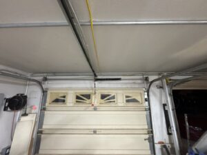 An old garage door with a clearly broken spring, indicating a repair job for Olympus Garage Door Repair in Tempe, AZ.