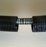 A close-up view of a broken garage door torsion spring, indicating a necessary repair by IGD Garage Door Repair in Renton, WA.