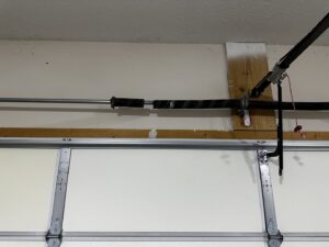 A close-up view of a broken garage door torsion spring, indicating a repair job by Steve's Overhead Door Company in Lafayette, IN.