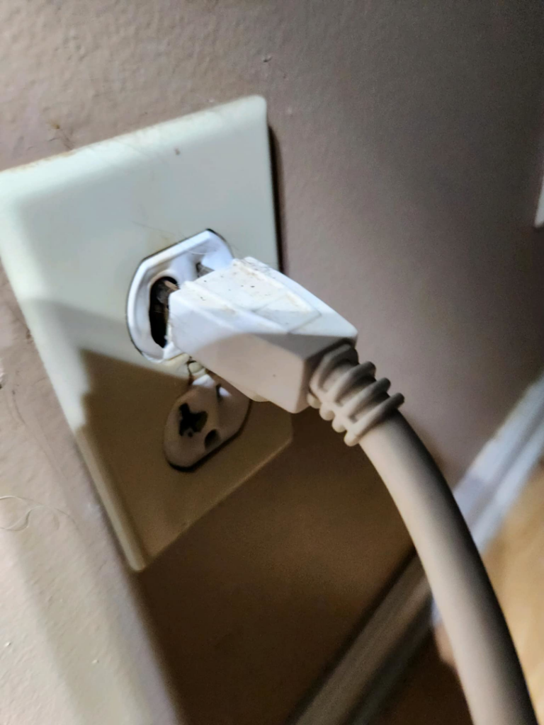 A close-up of a damaged electrical outlet with a broken ground pin, serviced by Wire Nutz LLC in Vancouver, WA