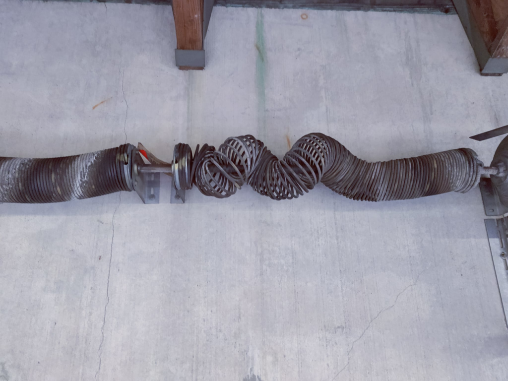 A clearly broken and tangled garage door torsion spring needing repair from Able Garage Door Service, LLC in Tucson, AZ.