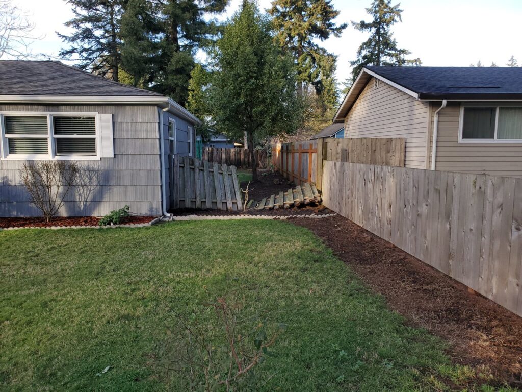 An old, broken wooden fence in a backyard, showing the need for repair or replacement by Fix-A-Fence LLC in Portland, OR.
