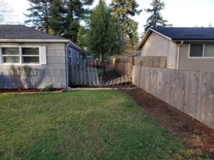An old, broken wooden fence in a backyard, showing the need for repair or replacement by Fix-A-Fence LLC in Portland, OR.