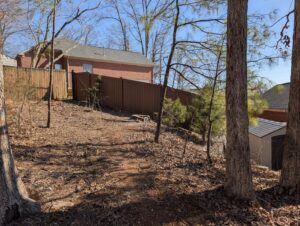 A brown composite fence installed on sloped terrain in a residential area by Alabama's Fencing in Huntsville, AL.