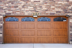 A beautiful brown garage door with decorative arched windows and scrollwork installed by Prutch's Garage Door in Colorado Springs, CO