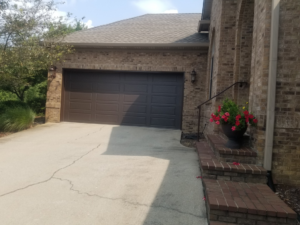 A brown garage door on a brick house, showcasing a completed project by Door-Tech LLC in Lexington, KY.