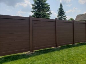 A modern brown horizontal privacy fence installed in a residential backyard by Sharper Image Fence in Fort Wayne, IN.