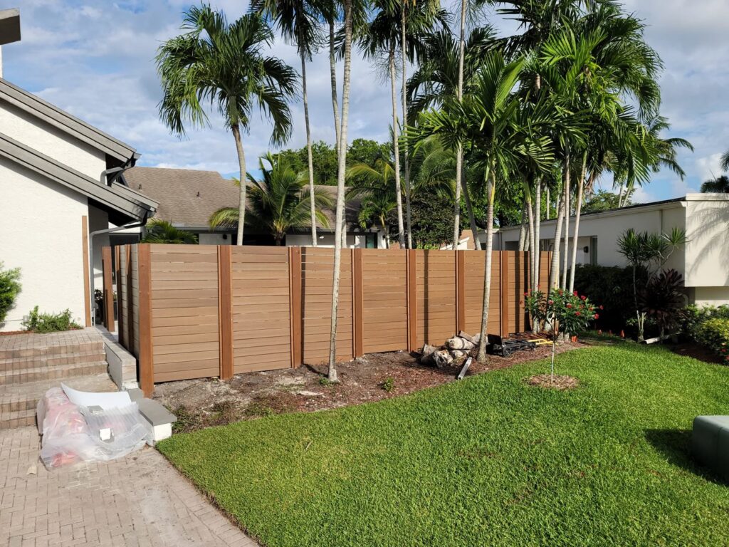 A long brown horizontal slat fence with wooden posts installed in a backyard by Miami Fence Installation Contractors in Miami, FL.