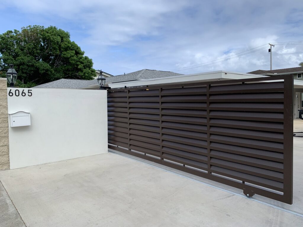 A brown horizontal slat sliding gate with house number and mailbox installed by A&D Services in Kapolei, HI.