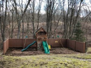 A sturdy brown privacy fence installed around a children's playset by AVA Fence & Railing LLC in Stamford, CT.