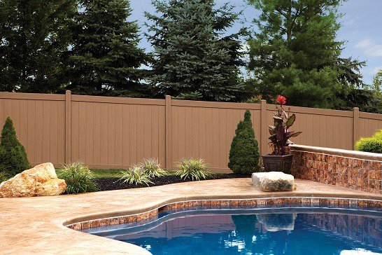 A sturdy brown privacy fence installed around a swimming pool by Austintown Fence in Youngstown, OH.
