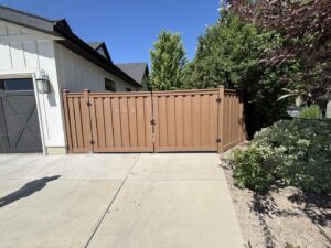 A completed brown privacy fence with double gates leading to a residential garage by All Over Fence Idaho in Jerome, ID