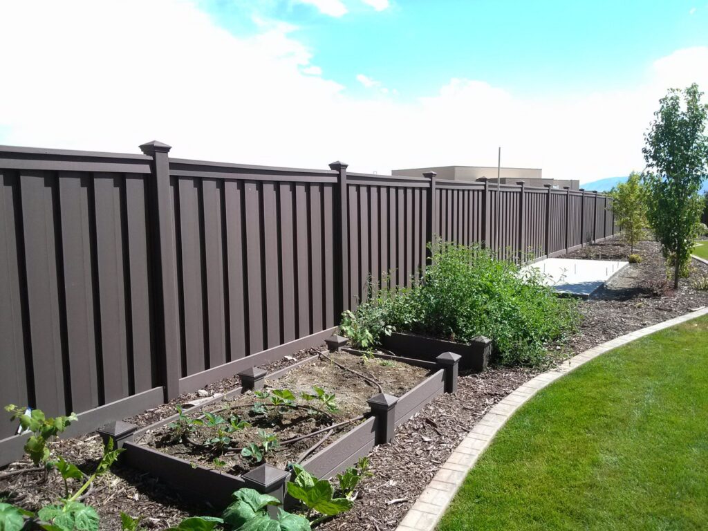 A sturdy brown privacy fence with integrated raised garden beds, installed by Stonehenge Fence & Deck in Orem, UT.