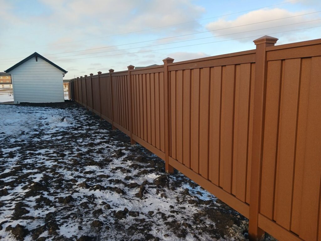 A brown privacy fence installed in a snowy yard by Aces Deck and Fence, LLC in Fargo, ND.