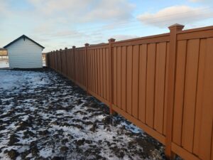 A brown privacy fence installed in a snowy yard by Aces Deck and Fence, LLC in Fargo, ND.