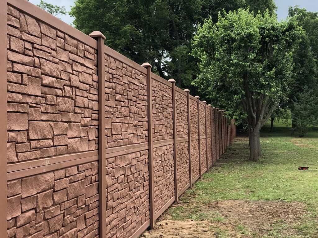 A long, brown textured privacy fence, possibly composite or faux stone, installed by RUCO Fence in Huntsville, AL.