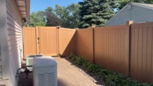 A brown vinyl privacy fence with a matching gate installed next to a house by MN Mike's Fence and Repair in Lakeville, MN.