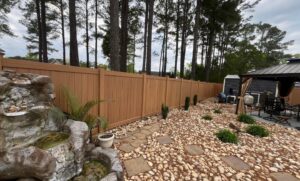 A brown vinyl privacy fence installed in a beautifully landscaped backyard by Fayetteville Fence Pros in Fayetteville, NC.