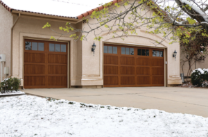 Brown wood panel garage doors with windows on a home in winter by Overhead Door Company of the Great Plains in Lawton, OK.