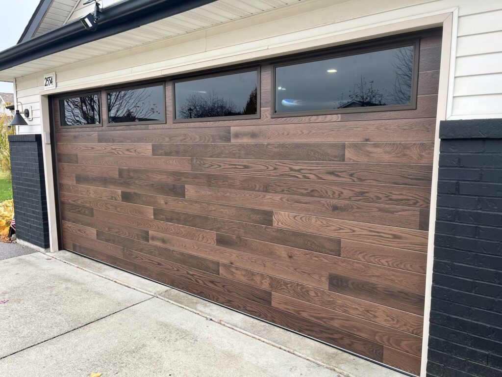 A stylish brown wooden-style garage door with top windows installed by Remarkable Door Company in Spokane, WA.