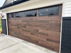 A stylish brown wooden-style garage door with top windows installed by Remarkable Door Company in Spokane, WA.