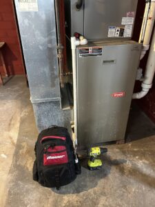 A Bryant furnace with a technician's backpack and drill nearby, indicating an HVAC service or installation job by Greenley Heating & Cooling in Waterloo, IA
