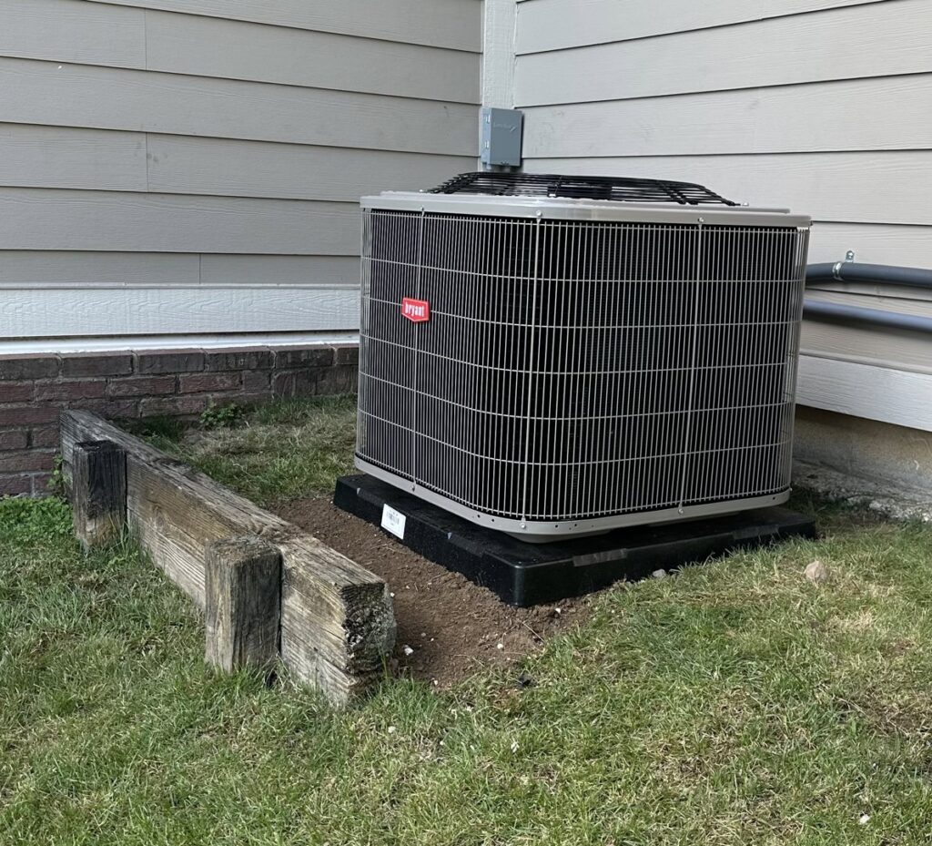A newly installed Bryant outdoor HVAC unit next to a residential building by Kelley Brothers LC in Livonia, MI.
