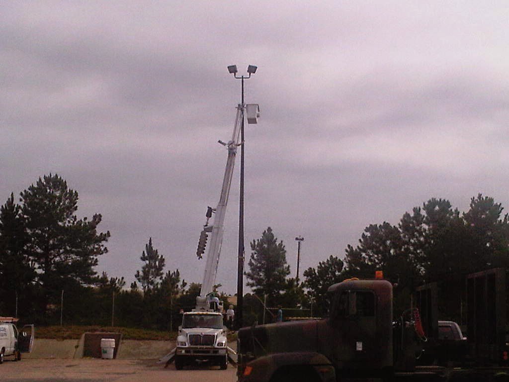 A bucket truck with its boom extended, working on a parking lot light pole for Argosy Electric, Inc. in Newport News, VA
