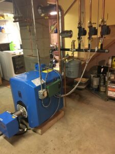 A blue Buderus boiler heating system with copper piping installed in a basement by Garrison City HVACR in Dover, NH