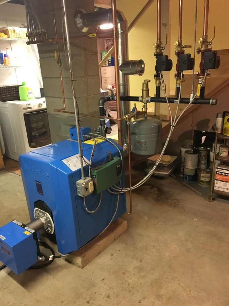 A blue Buderus boiler heating system with copper piping installed in a basement by Garrison City HVACR in Dover, NH