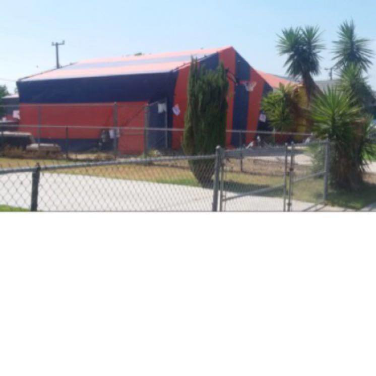 A commercial building covered in orange and black fumigation tenting by Intensive Pest Control in Long Beach, CA.