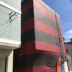A section of a building covered in red and black fumigation tenting by Intensive Pest Control in Long Beach, CA.