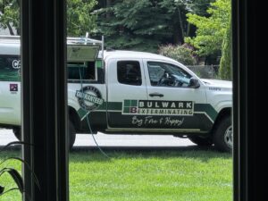 A Bulwark Exterminating service truck parked outside a home, viewed from inside, in Greensboro, NC.