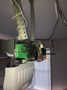 A close-up of a burnt circuit board inside a garage door opener, indicating an electrical repair job by Brooker Electric in Roswell, GA.