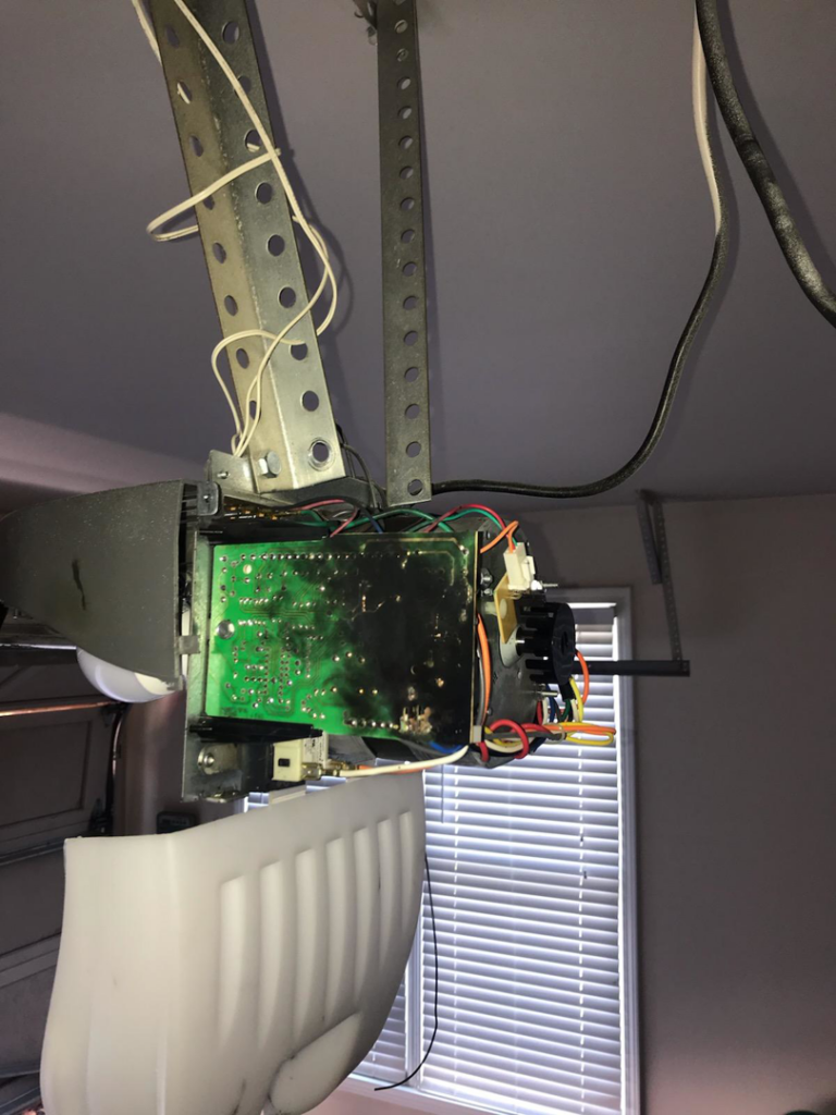 A close-up of a burnt circuit board inside a garage door opener, indicating an electrical repair job by Brooker Electric in Roswell, GA.