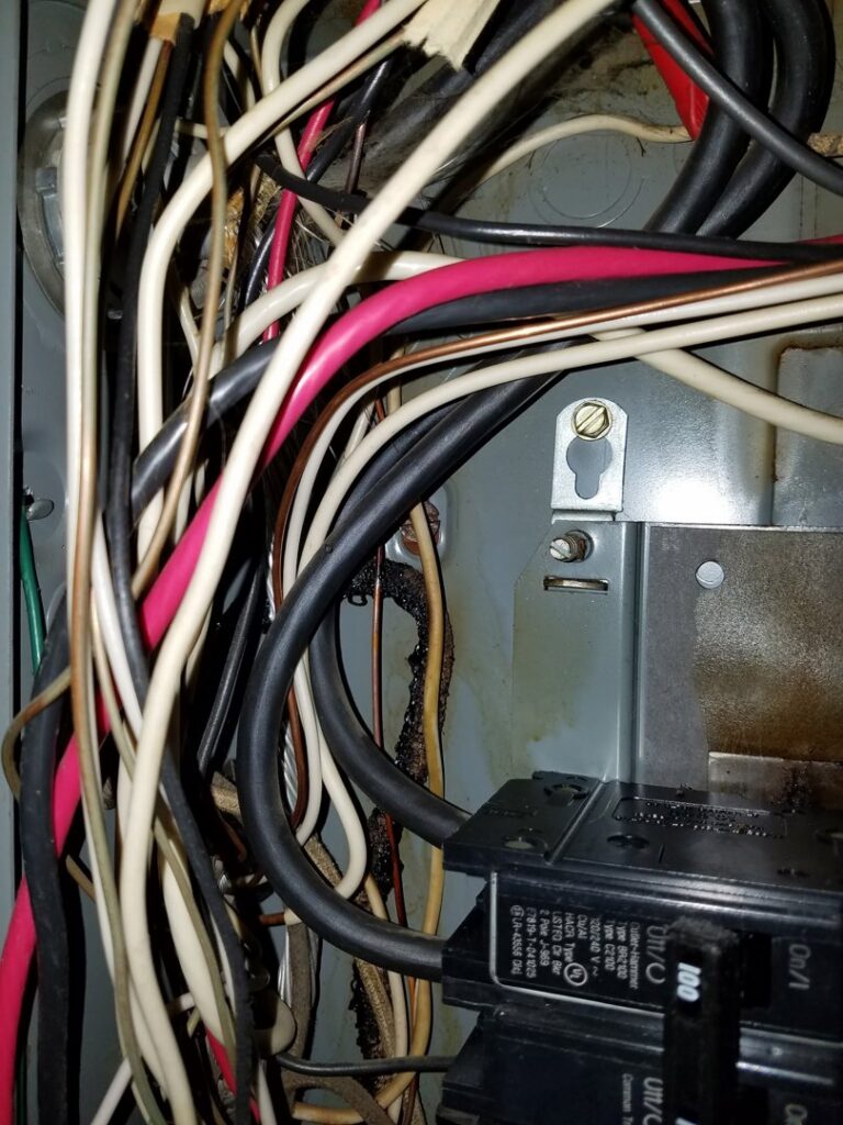 Close-up of burnt and damaged electrical wiring inside a panel, indicating a repair job by Jeremy Electrical in Roeland Park, KS.