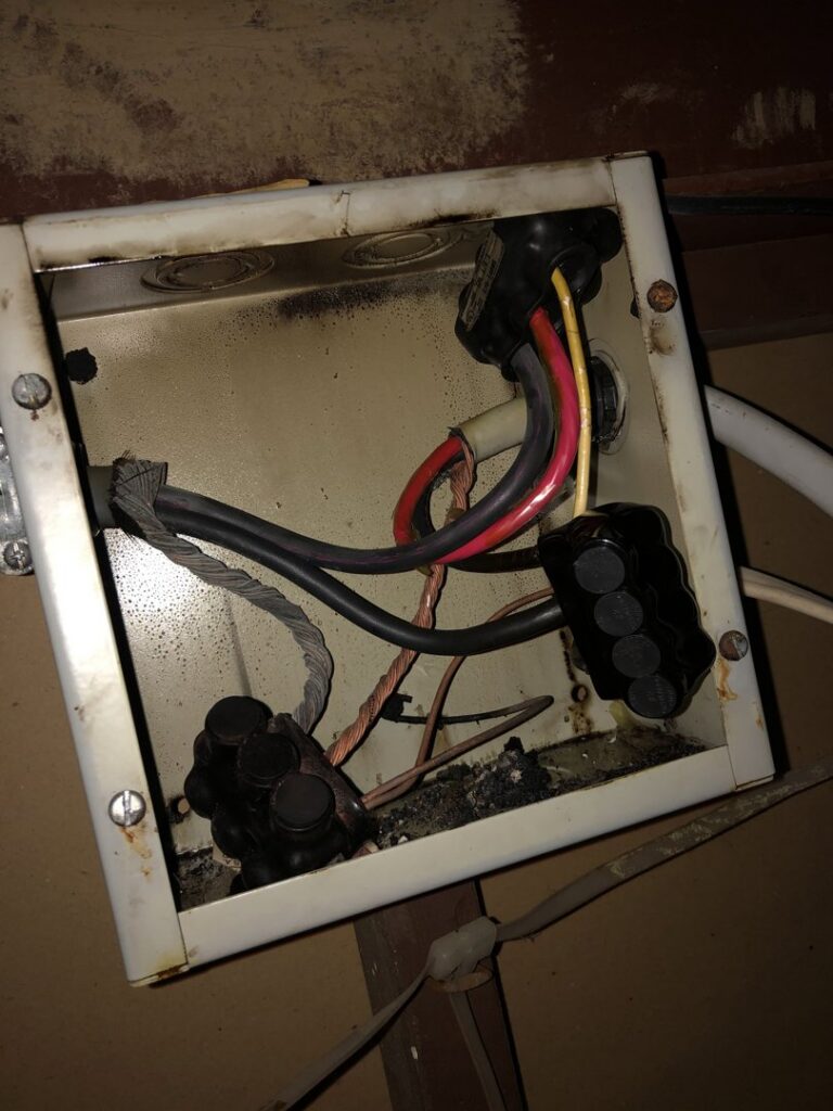 A burnt electrical junction box with damaged wires, indicating an electrical fault requiring repair by Buckeye Electric of Upper Arlington, LLC in Columbus, OH.