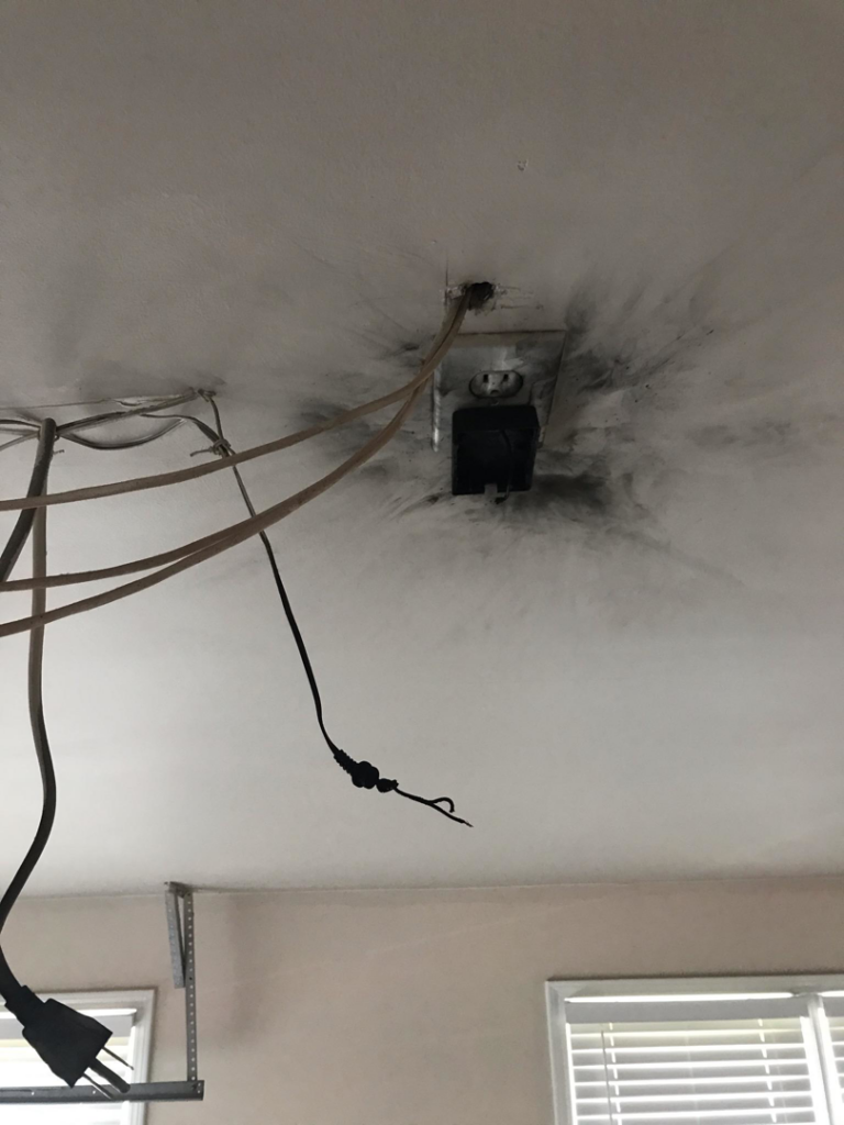A burnt electrical outlet on a ceiling, showing damage that Brooker Electric in Roswell, GA can repair.