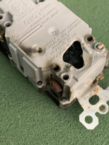 A severely burnt electrical outlet or breaker, indicating a serious electrical issue handled by Hulett Electric & Father in Shaftsbury, VT.