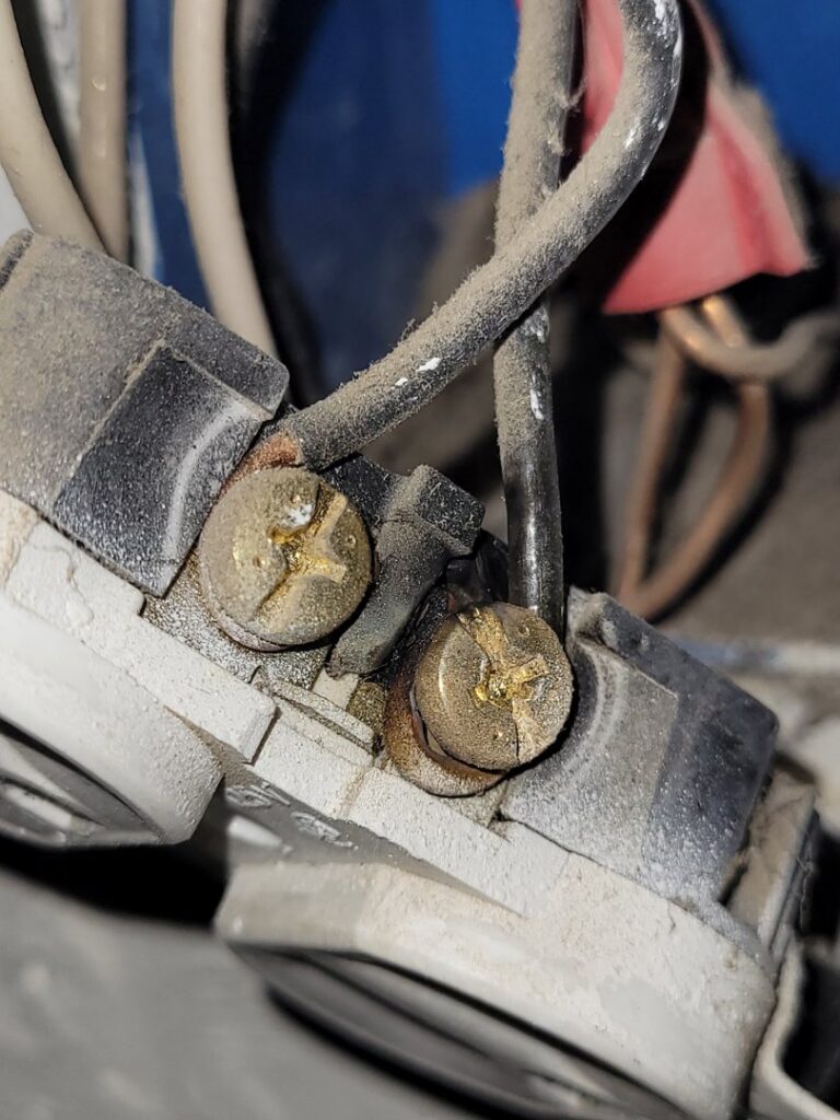 A close-up of a burnt electrical outlet with scorch marks, indicating a repair job by Gold Electric INC in Bend, OR.