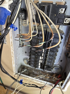 An electrical panel showing burnt wires and circuit breakers, indicating a repair job by Hummingbird Electric Inc. in Tulsa, OK.