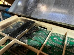 A burnt circuit board from an HVAC unit, indicating a repair service performed by Air Masters, Inc. in Port Orchard, WA.