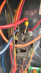 A close-up of burnt wiring and a contactor inside an HVAC unit, indicating a repair by Bruce Heating & Air in Kennewick, WA.