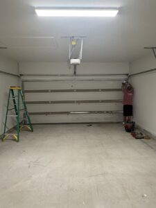 A worker from Cajun Doors & More in Lafayette, LA, wearing a company shirt and working on a wooden door panel outdoors.