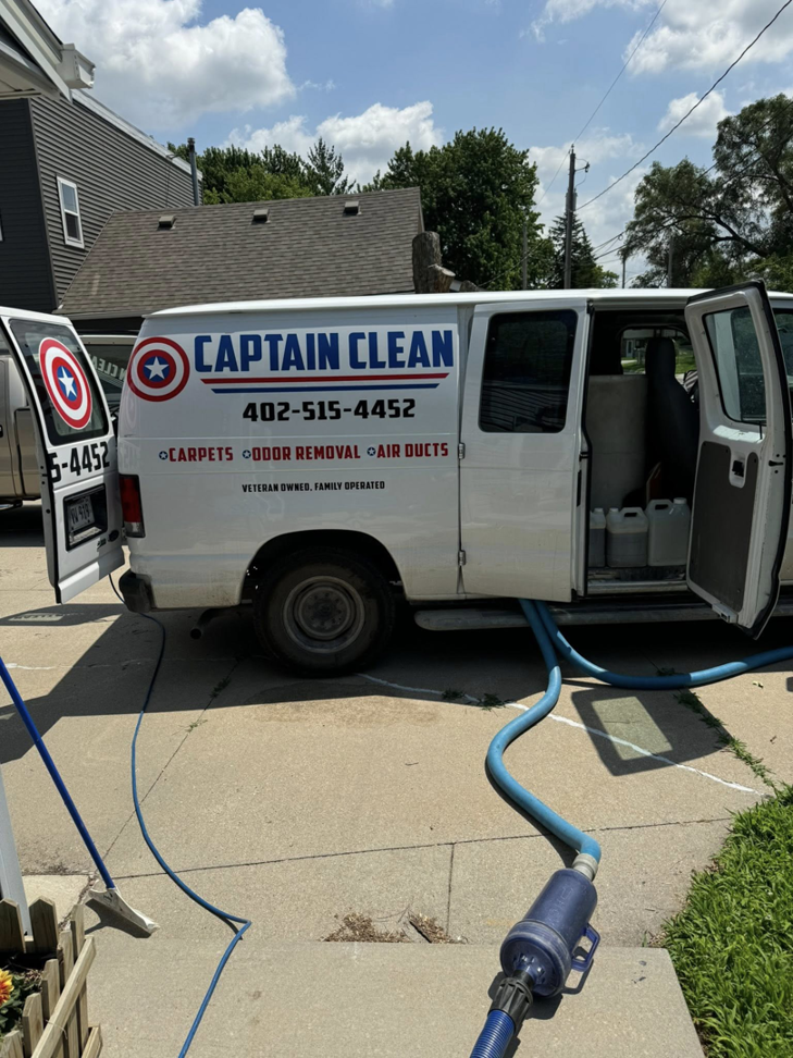 Captain Clean service van with hoses connected, ready for a carpet cleaning job on-site in Muncie, IN.